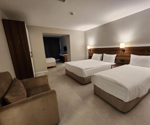 a hotel room with two beds and a couch at Lulubay Rooms & Suites in Kusadası