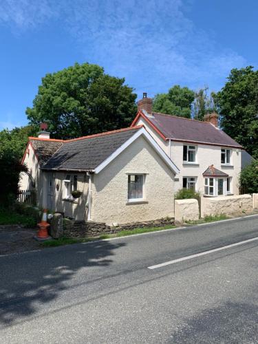 a white house sitting on the side of a road at Newfoundland Cottage in Whitechurch