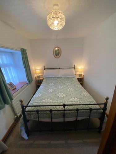 sypialnia z łóżkiem z żyrandolem i oknem w obiekcie Newfoundland Cottage w mieście Whitechurch