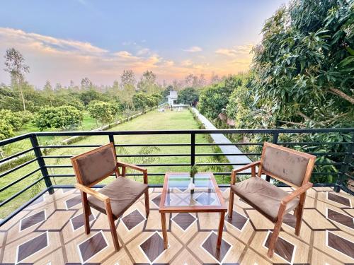 two chairs and a table on a balcony at The White Oak Corbett Spa & Resort in Rāmnagar