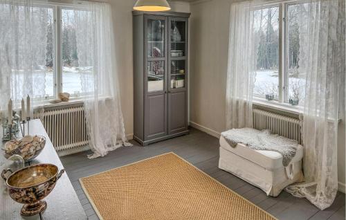 a living room with a chair and a table and windows at Cozy Home In Nrkesberg With Outdoor Swimming Pool in Närkesberg