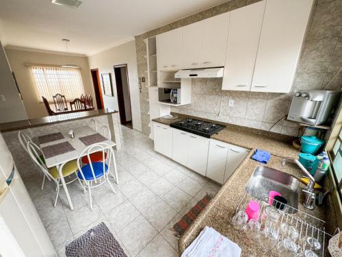 パスト・デ・ミナスにあるCasa Completa com Churrasqueira em Patos de Minasのキッチン(白いキャビネット、シンク付きテーブル付)