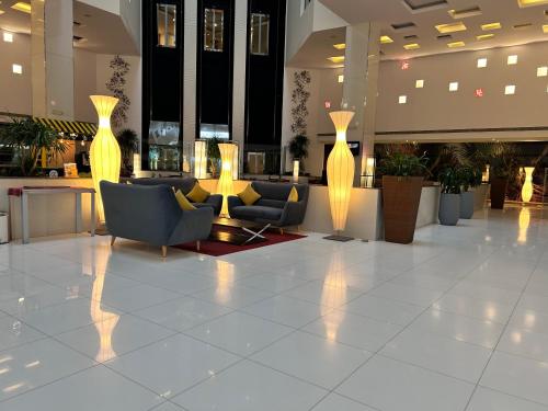 a lobby with chairs and vases in a building at Golden Tulip Muscat in Muscat