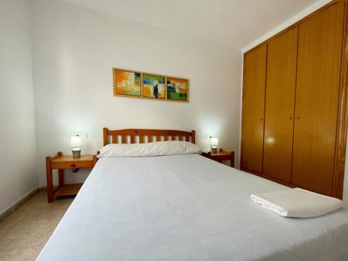 a bedroom with a large white bed and a wooden cabinet at Apartamentos Estacion Oropesa 3000 in Oropesa del Mar