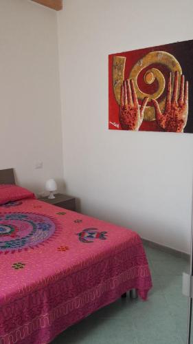 um quarto com uma cama com um edredão rosa em Serenissima em Santa Margherita di Pula