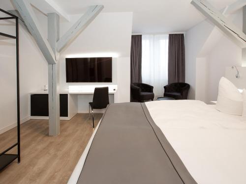 a hotel room with a bed and a desk at DORMERO Hotel Worms in Worms