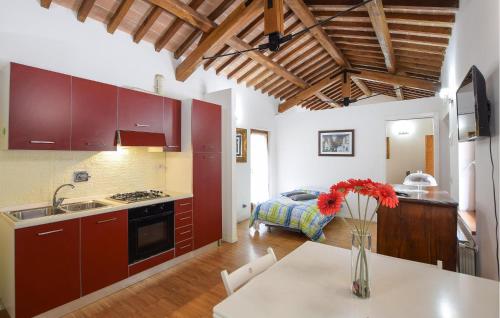 a kitchen with red cabinets and a table with a vase of flowers at Gorgeous Apartment In Gubbio With Wifi in Gubbio