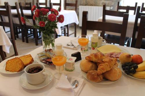 a table with plates of breakfast foods and a vase of flowers at Quinta Vale do Homem in Amares