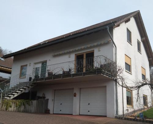a white house with a balcony and two garage doors at Ferienwohnung Monteurwohnung Pusteblume in Duderstadt