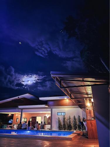 a house at night with people sitting on the patio at Manee Poolvilla in Khanom
