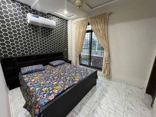 um quarto com uma cama com colcha floral e uma janela em Uptown Residences em Gujrānwāla