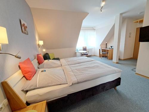 Pokój hotelowy z dużym łóżkiem z pomarańczowymi poduszkami w obiekcie Gasthaus Zum Lindenwirt w mieście Weißehütte