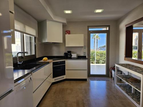 a kitchen with white cabinets and a large window at Antonia in Can Picafort