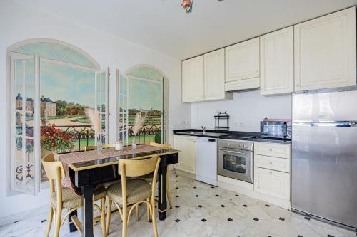 une cuisine avec des armoires blanches et une table et des chaises dans l'établissement Grand et central, 8e près Élysée, à Paris