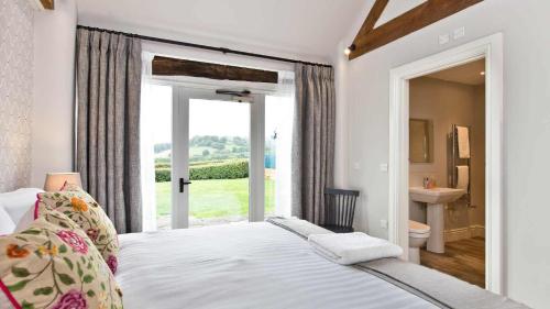 1 dormitorio con 1 cama y baño con ventana en Manifold Barns en Belper