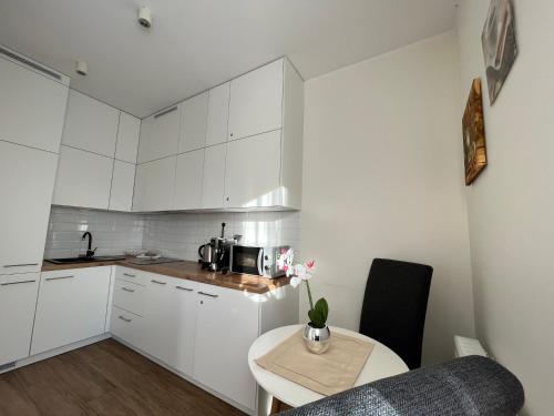 una pequeña cocina con armarios blancos, mesa y sidra de mesa en Apartamenty Kielce- Apartament Zacisze przy Baseny Tropikalne, Kadzielnia, parking, faktura en Kielce