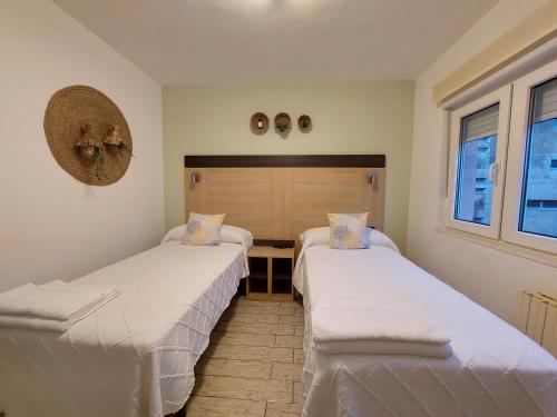 duas camas num quarto com lençóis brancos em Pensión Cabezas em Lugones
