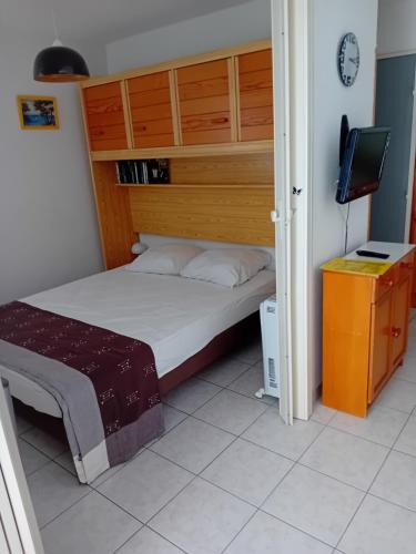 une petite chambre avec un lit et une télévision dans l'établissement Appartement P2 Le Californie Grau du Roi, au Grau-du-Roi