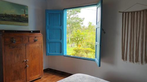 a bedroom with a blue window and a dresser at Buriti EcoH RNT56521, via Termales Santa Rosa de Cabal in Santa Rosa de Cabal