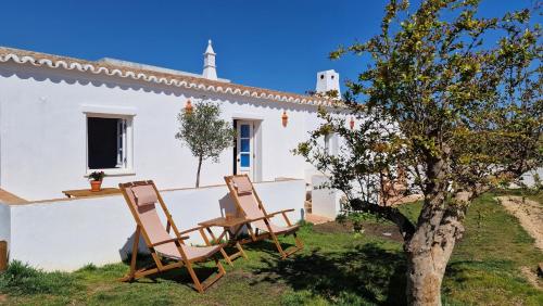 ein Haus mit zwei Stühlen und einem Baum in der Unterkunft Milagres de Santa Rita in Vila Real de Santo António