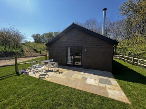 a building with a patio with a table and chairs at Cherry Lodge in Godshill