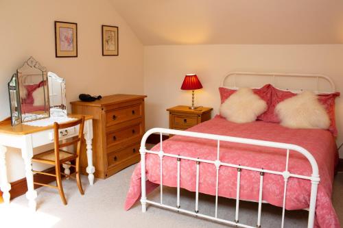 a bedroom with a bed and a table and a mirror at Fedwen Uchaf Tresaith in Penbryn