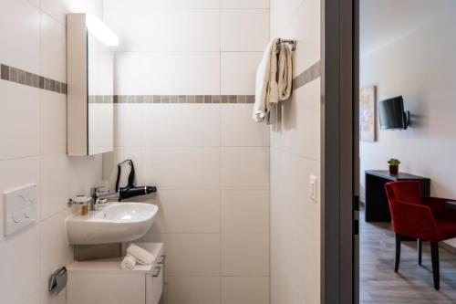 a white bathroom with a sink and a toilet at Motel-Résidence Ô Pied à Terre in Montilliez