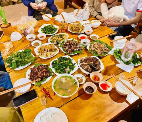 a group of people sitting around a wooden table with food at Homestay Chân Núi in Sa Pả