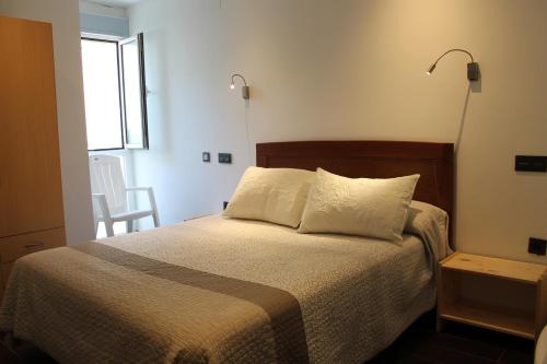 a bedroom with a bed with two pillows and a window at Apartamentos turísticos Vistademar in Luarca