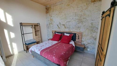 ein Schlafzimmer mit einem Bett mit roten Kissen in der Unterkunft Les Coccinelles in Adilly