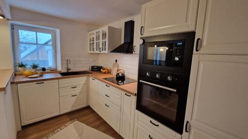 a kitchen with white cabinets and a black oven at Relax chata Helena Mikulášovice - Tschechische und Sächsische Schweiz in der Nähe in Mikulášovice