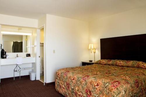 a hotel room with a bed and a bathroom at Sands Inn & Suites in Woodward