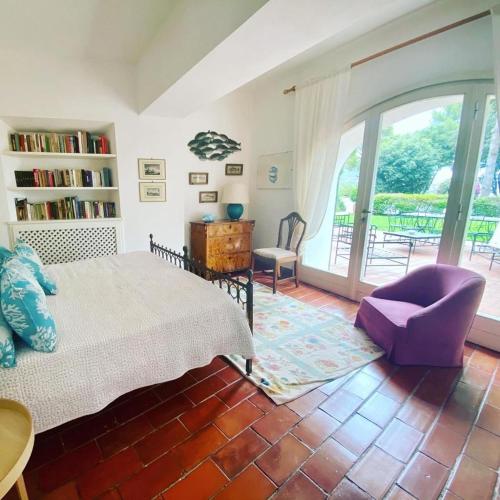 een slaapkamer met een bed, een stoel en een raam bij Villa Bianca in Porto Ercole