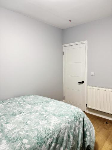 a white bedroom with a bed and a door at Nice and Pleasant in Thornton Heath