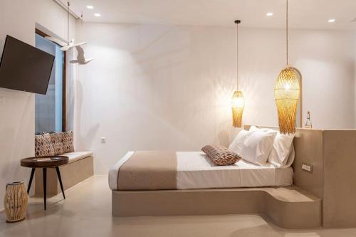 a bedroom with a bed and a tv and a chair at Kohili Suite Stegna Beach in Archangelos