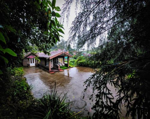 a river with two small buildings in the middle at Woodside Bungalow1 in Ooty
