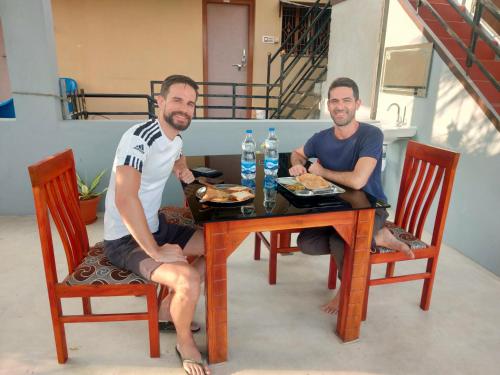 dos hombres sentados en una mesa con platos de comida en Little Dream Homestay Hampi, en Hampi