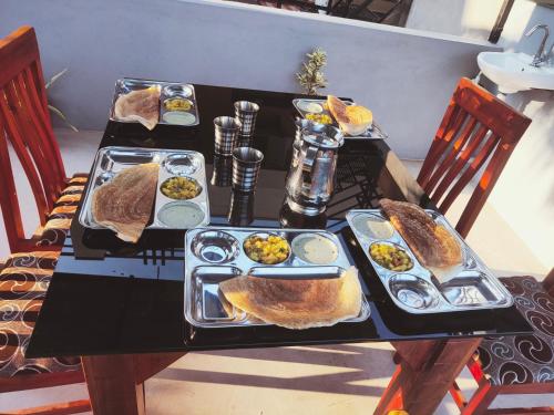 a black table with plates of food on it at Little Dream Homestay Hampi in Hampi