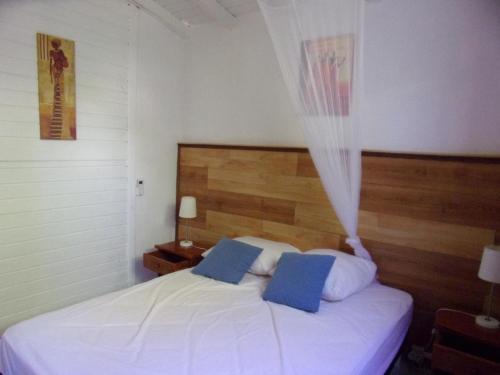 una camera da letto con un letto bianco con due cuscini blu di  La kaz a coyoky ad Anse-Bertrand