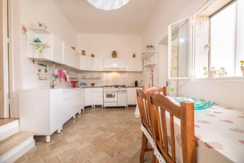 a kitchen with white cabinets and a table and chairs at La Dimora Lucia by Paf in tour in Torre Suda