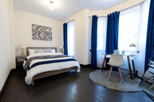 een slaapkamer met een bed met blauwe gordijnen en een bureau bij E10-1 Designer East Village Townhouse 1BR in New York
