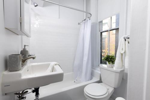 a white bathroom with a sink and a toilet at E10-1 Designer East Village Townhouse 1BR in New York