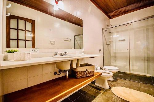 a bathroom with a toilet and a sink and a shower at Tília Pousada de Charme in Campos do Jordão