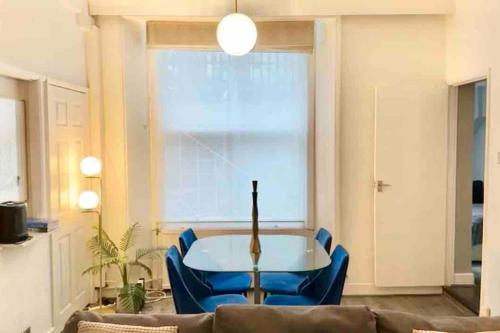 a living room with a table and blue chairs at Cozy 1 bed in the heart of South Kensington in London