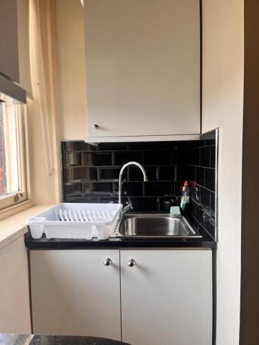 a kitchen with a sink and a black tile wall at Ullet Suites in Liverpool