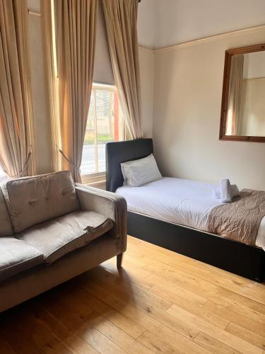 a room with two beds and a couch and a window at Ullet Suites in Liverpool