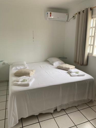 uma cama branca com lençóis brancos e almofadas em Casa geminada 1 em Florianópolis