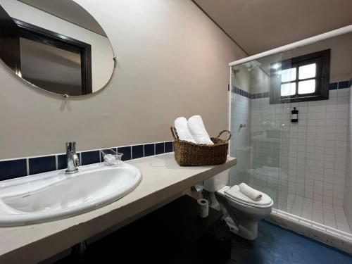 a bathroom with a sink and a toilet and a mirror at Casario 1915 Pousada in Morretes