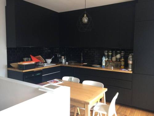 una cucina con pareti nere e tavolo e sedie in legno di Maison à 2 pas de Paris ! a Bagnolet