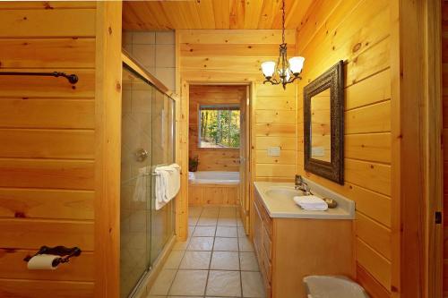 ein Bad mit einem Waschbecken, einer Dusche und einem Spiegel in der Unterkunft Emerald City Lights #203 in Gatlinburg